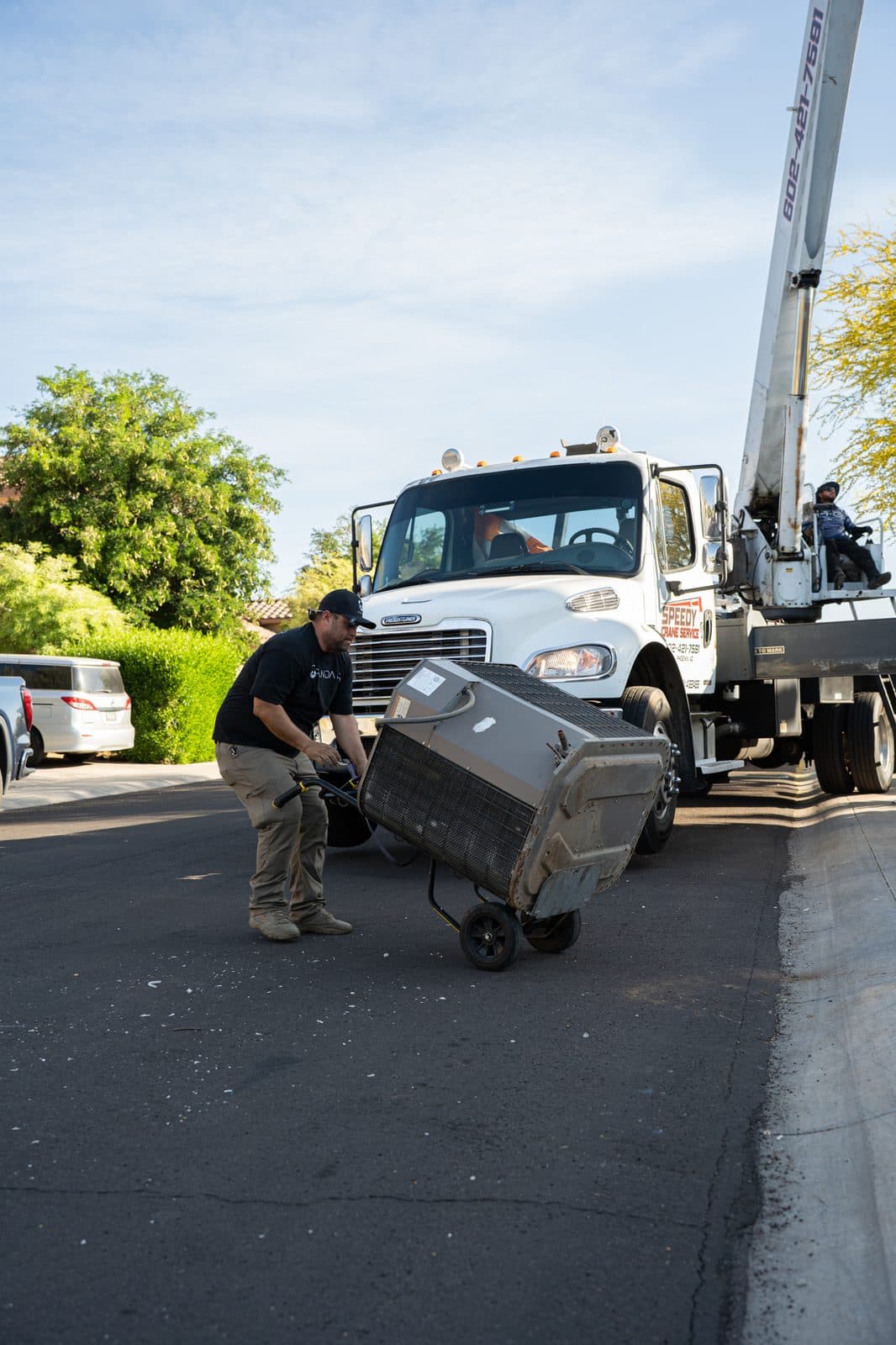 Technician wheeling an old condensing unit away on a dolly